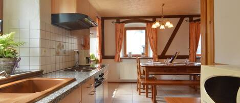 A kitchen with granite countertops, wooden cabinets, a built-in stove, and a dining area with a wooden table and chairs.
