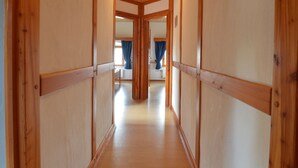 A wooden hallway with a ceiling fan, leading to a room with a bed and a window with blue curtains. - Holiday Home in Butgenbach Near the Lake (Buetgenbach)