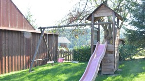 A wooden playhouse with a slide in a backyard. - Nature Escape in Martelange (Martelange)