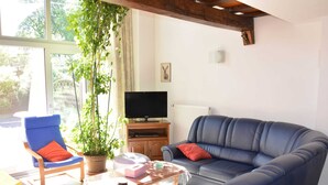 A living room with a blue sofa, a blue armchair, a coffee table, a television, and a potted plant. - Nature Escape in Martelange (Martelange)