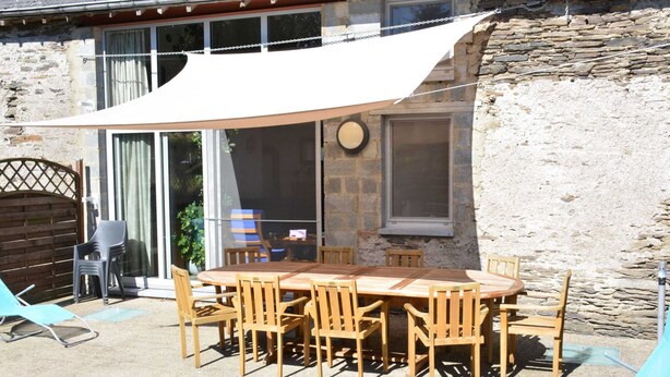 An outdoor patio with a wooden table and chairs, a white awning, and a stone wall. - Nature Escape in Martelange (Martelange)