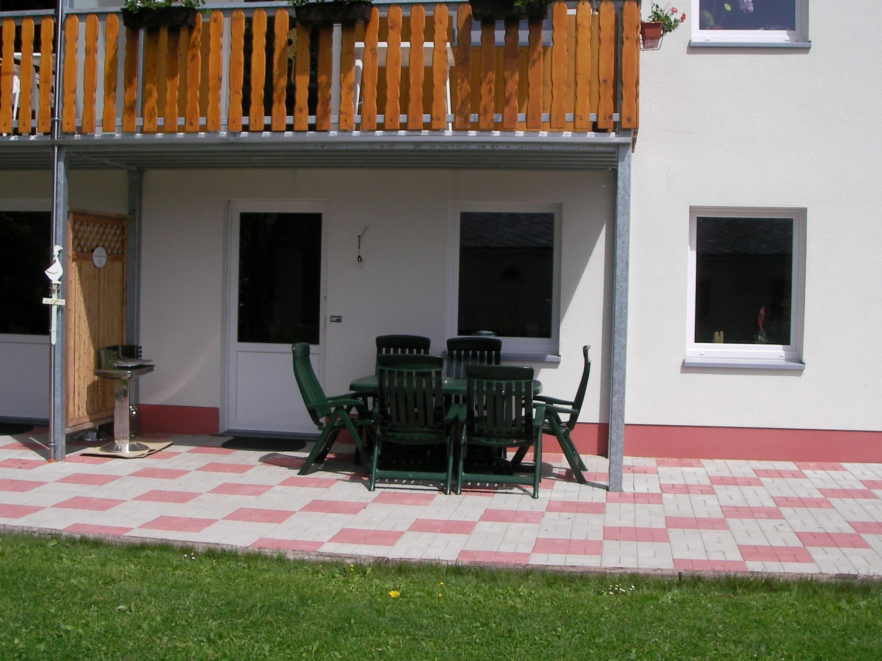 Ein überdachter Patio-Bereich mit Schachbrettboden, Tisch und Stühlen sowie einem Holzzaun.