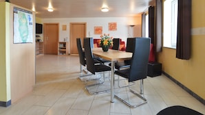 A dining area with a wooden table and black chairs, a map on the wall, and a window with curtains. - Holiday Home in Burg Reuland (Burg-Reuland)