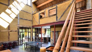 A spacious room with a ping pong table, wooden chairs, and a bamboo staircase. - Pleasant Holiday Home in Erezée Ardennes with Hot Tub, Sauna (Erezee)