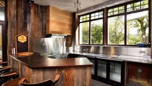 A kitchen with a wooden island, stainless steel appliances, and a large window with a view of trees. - Pleasant Holiday Home in Erezée Ardennes with Hot Tub, Sauna (Erezee)