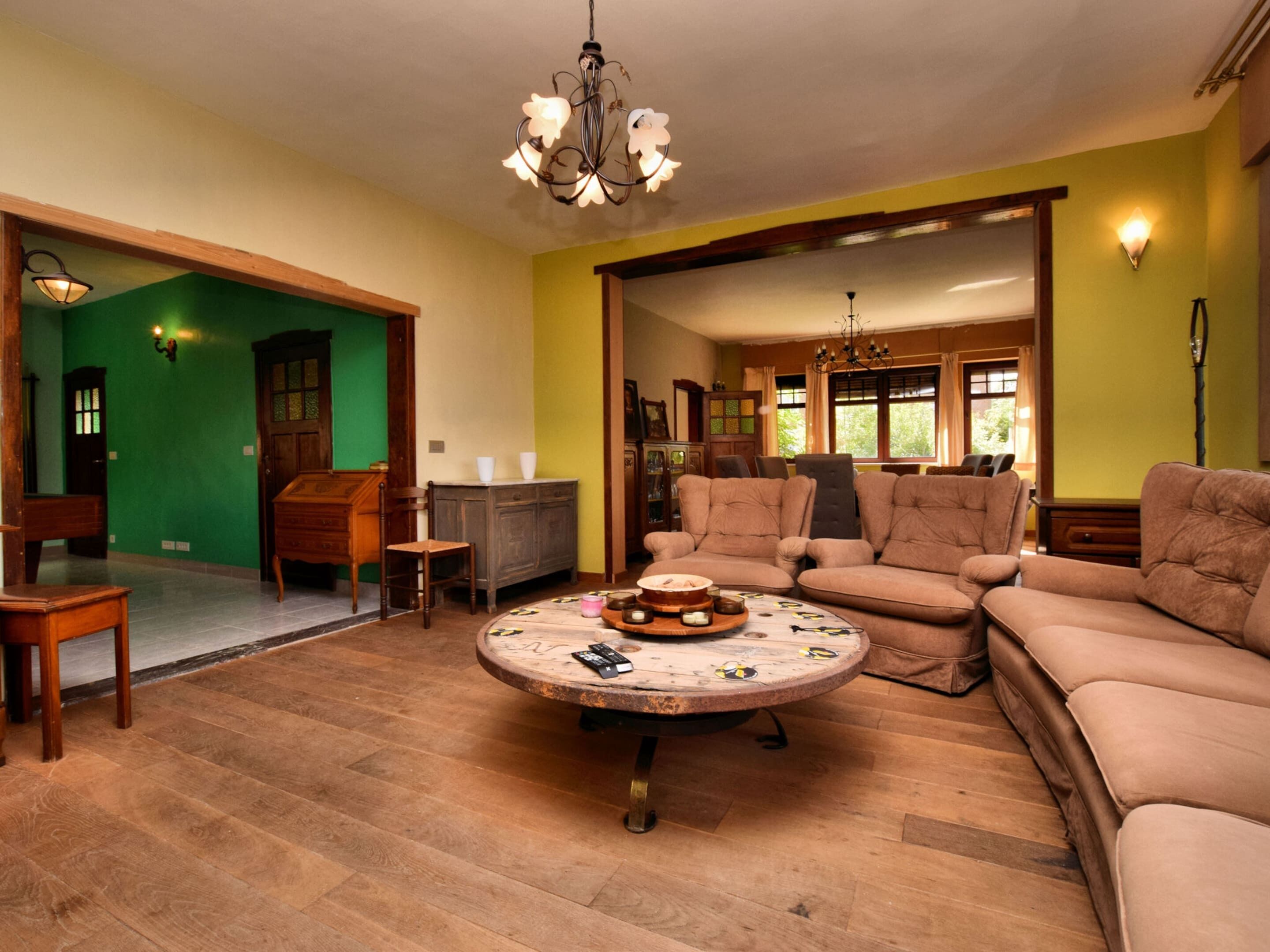 Ein geräumiges Wohnzimmer mit einem runden Couchtisch, einem beigen Sofa und Holzboden.
