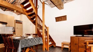 A dining area with a wooden staircase, a television, and a small cabinet. - Nice Apartments in a Monumental Square Farm (Vise)