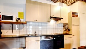 A modern kitchen with white cabinets, a black dishwasher, and a stainless steel sink. - Nice Apartments in a Monumental Square Farm (Vise)