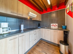 Una cucina moderna con mobili in legno, piano cottura integrato, macchina da caffè e cestino.