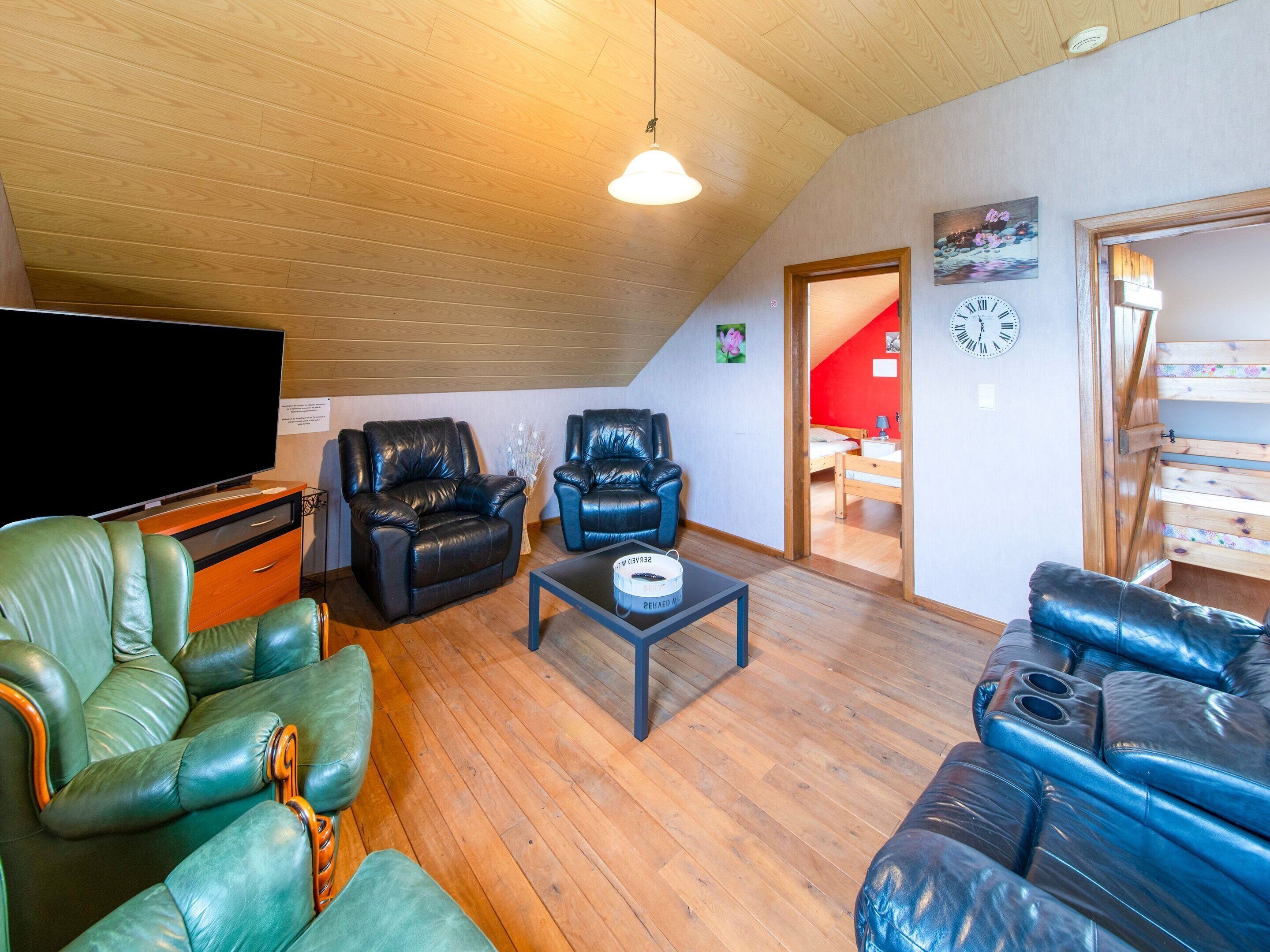 Ein Loft-Zimmer mit Holzboden, einem Flachbildfernseher, Ledersofas, einem Couchtisch und einer Treppe zu einer erhöhten Ebene.