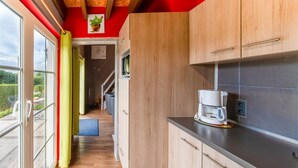 Une cuisine moderne avec des meubles en bois, une machine à café et une vue sur l’extérieur.