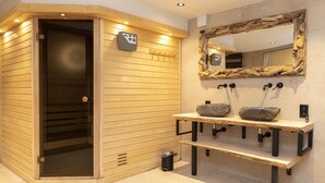A sauna with a wooden exterior, a glass door, and a control panel on the wall. - Cosy Chalet in Odeigne with Hot Tub (Manhay)