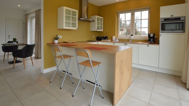 A modern kitchen with a central island, white cabinets, and a yellow accent wall. - Sint-amands Country Escape (Puurs-Sint-Amands)