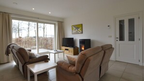 A living room with a sofa, a coffee table, a TV, and a fireplace. - Sint-amands Country Escape (Puurs-Sint-Amands)