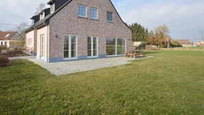 A two-story house with a brick exterior, large windows, and a patio area with a table and chairs. - Sint-amands Country Escape (Puurs-Sint-Amands)