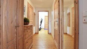 Un couloir doté d’un plancher en bois et de portes, qui mène à une pièce contenant du matériel d’exercice.