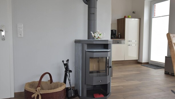 A modern kitchen with a built-in wood stove, a wicker basket, and a coffee maker. - Ferienhaus in Gross Schwansee mit Sauna (Kalkhorst)