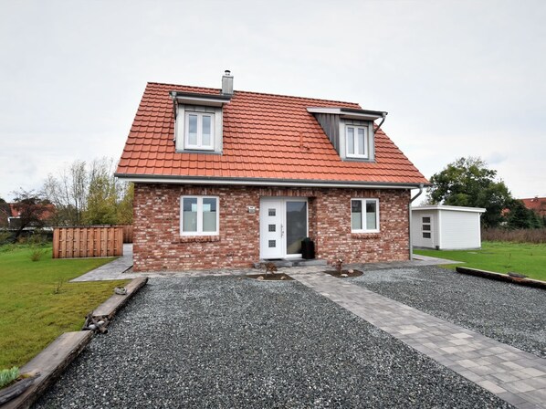 A two-story house with a red-tiled roof, a brick facade, and a gravel driveway. - Ferienhaus in Gross Schwansee mit Sauna (Kalkhorst)