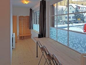 A room with a large window, a wooden bench, a radiator, and a table with a chair. - Ferienwohnung in Wildemann (Clausthal-Zellerfeld)