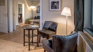 Ett modernt vardagsrum med en soffa i läder, ett runt bord med en glasskiva och en golvlampa.