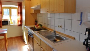 A kitchen with wooden cabinets, a stainless steel sink, a microwave, and a stove.