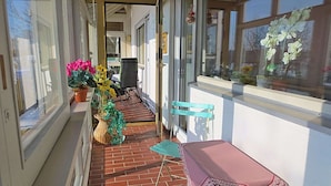 A covered outdoor area with a brick floor, a table with a pink tablecloth, and two chairs. - Apartment in Goggersreut mit Terrasse (Roehrnbach)