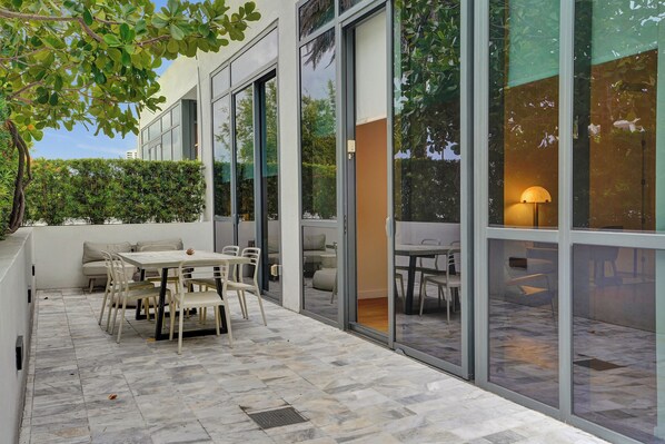 An outdoor patio with a dining table and chairs, a sofa, and a lamp. - 17WEST Apartments by Stay Hospitality (Miami Beach)