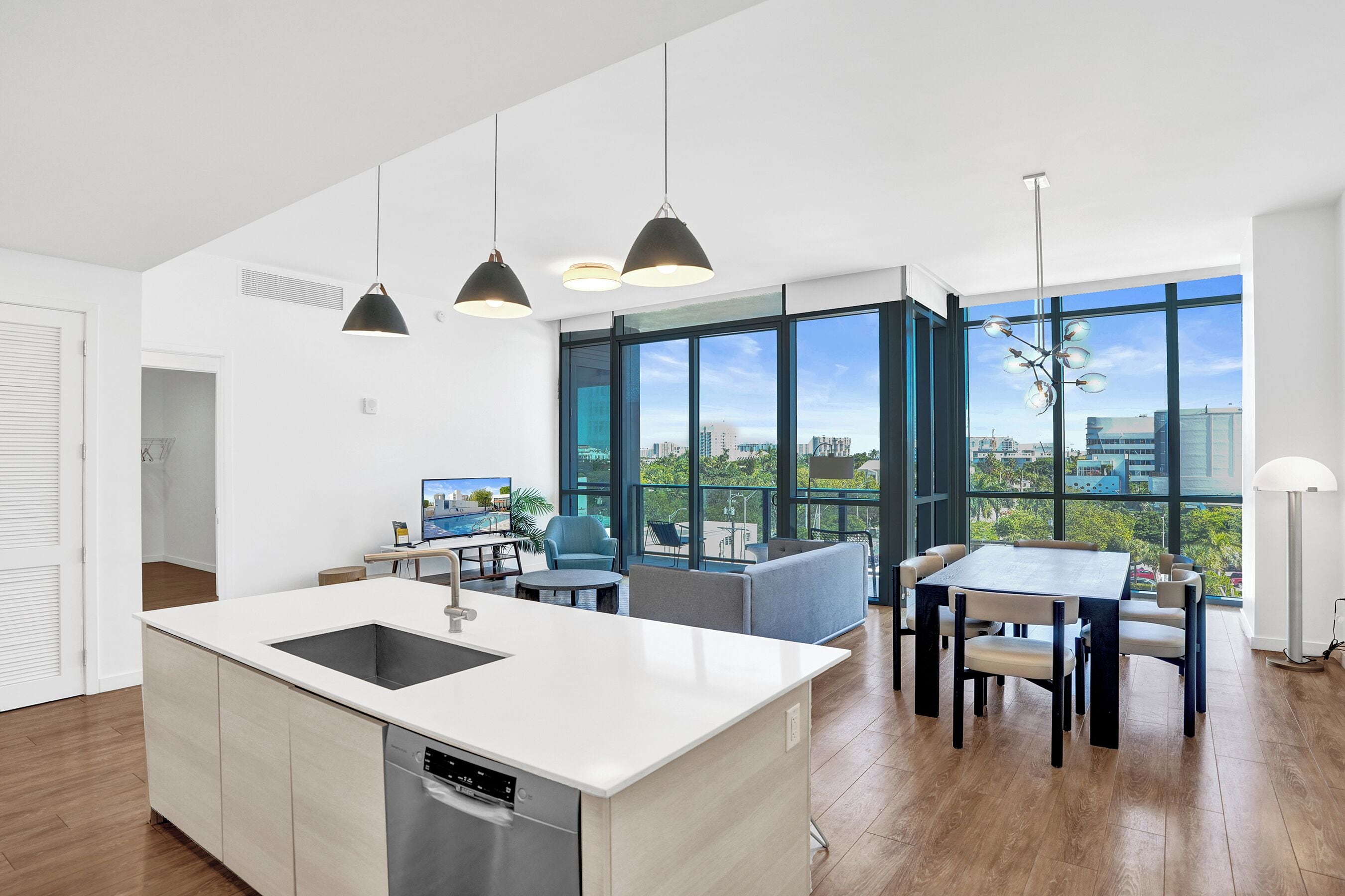 Een moderne keuken met een centraal eiland, een eetgedeelte met een tafel en stoelen, en grote ramen met uitzicht op de stad.