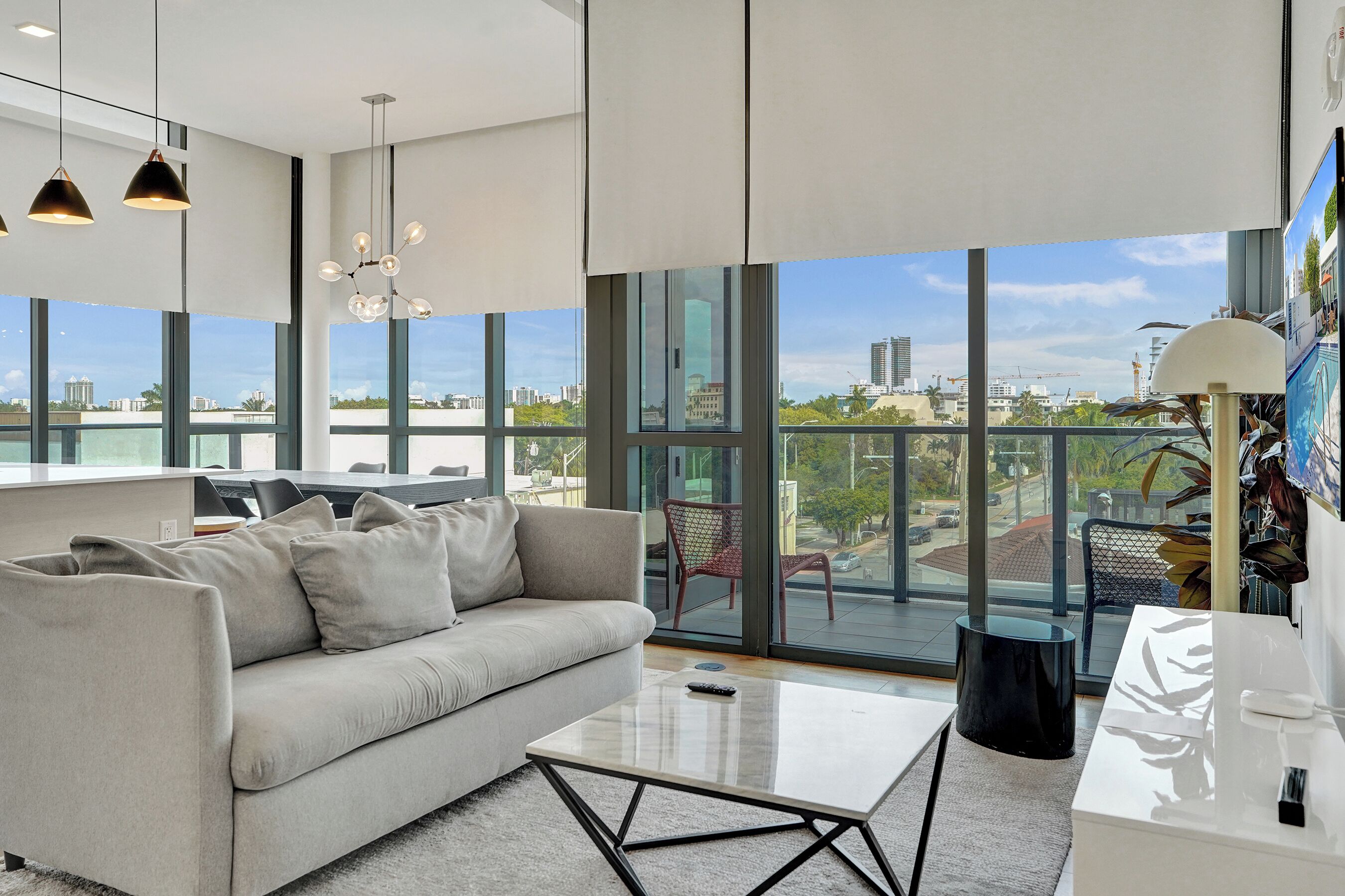 Un salon moderne avec un canapé, une table basse et de grandes fenêtres donnant sur la ville.