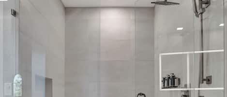 A modern bathroom with a freestanding bathtub, glass shower enclosure, and built-in storage shelves.