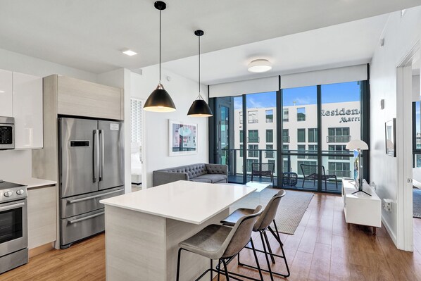 A modern kitchen with stainless steel appliances, a central island, and a dining area with bar stools.