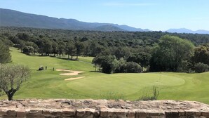 A golf course with a stone wall in the foreground, surrounded by trees and distant mountains. - Private Pool in Provence (La Motte)