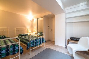 Ein Schlafzimmer mit zwei Betten, einem Spiegel, einem Schreibtisch mit Stuhl und einer Tür.