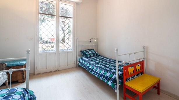 A bedroom with a single bed, a wooden chair, a small table, and a window with a view of trees. - Elegant Seaside Villa in Eze (Èze)