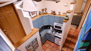A compact kitchen with blue cabinets, a microwave, and a stove. - Casita G - 1 Bed, 1 Bath (Loft Style, Stairs) (Santa Fe)
