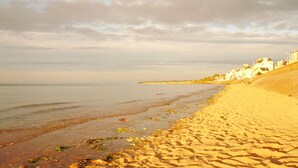 A beach with sand, water, and buildings along the shore. - Nature Hideaway in St Germain du Pert (Saint-Germain-du-Pert)
