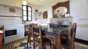 A kitchen with a stove, oven, dining table, chairs, and a large mirror.