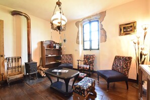 A cozy room with a fireplace, wooden furniture, and a window with natural light. - Cottage in France With Garden Near Lake (Montaron)