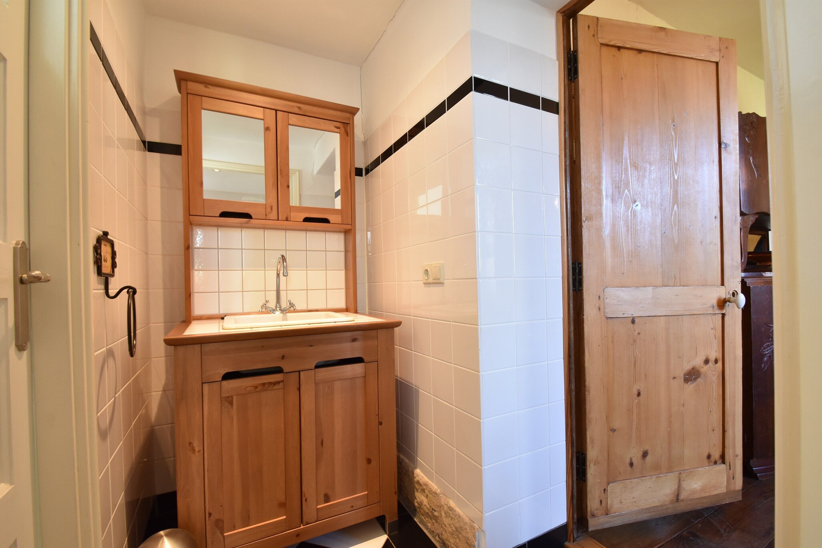A bathroom with wooden cabinets, a sink, and a door.