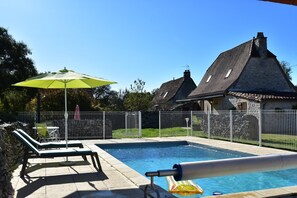 A swimming pool with lounge chairs and an umbrella, surrounded by a stone wall and a metal fence. - Holiday Home in Gramat With Private Pool (Gramat)