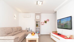 A modern living room with a beige sofa, a white coffee table, and a flat-screen TV on a white wall. - Villa 1771 (Vodnjan)