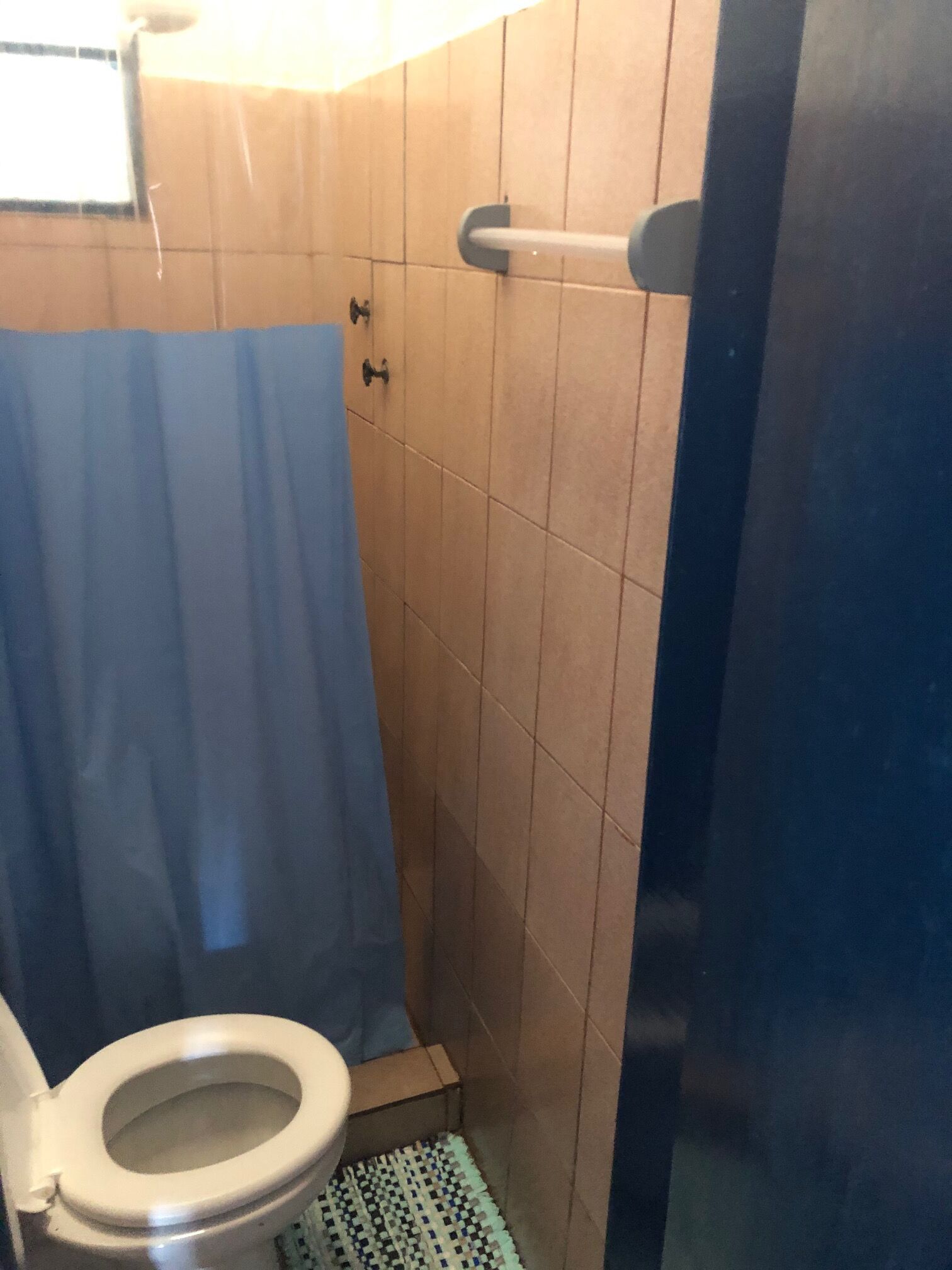 Een kleine badkamer met toilet, douchegordijn en betegelde wanden.