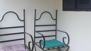 Una habitación con dos sillas de estructura metálica, una con cojín turquesa y la otra con cojín púrpura.