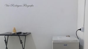 Una habitación compacta con una pequeña mesa, un refrigerador y un enchufe en la pared.