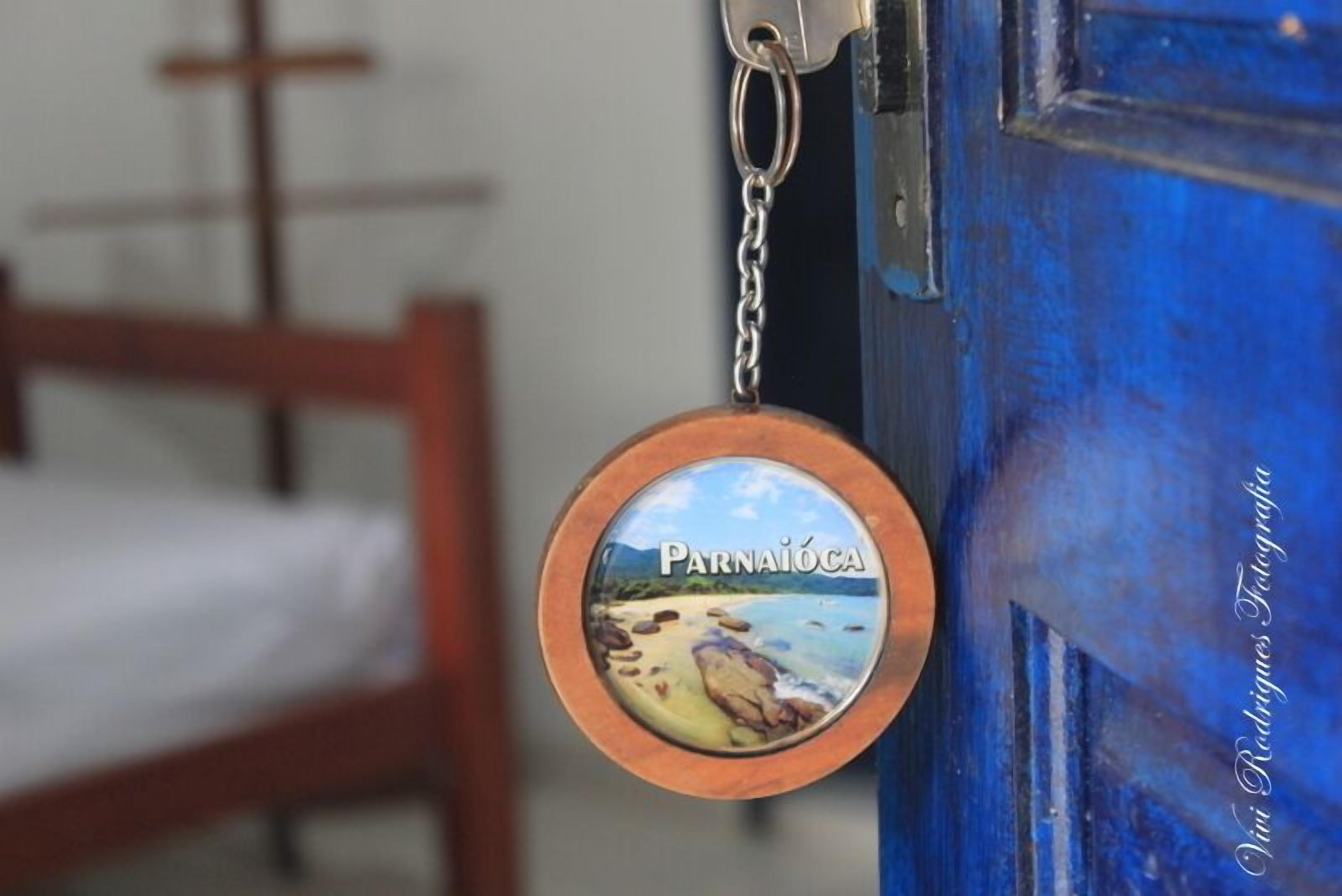 Ein Schlüsselanhänger mit einer Strandansicht und dem Schriftzug 'Parnaíba' auf einer blauen Tür.