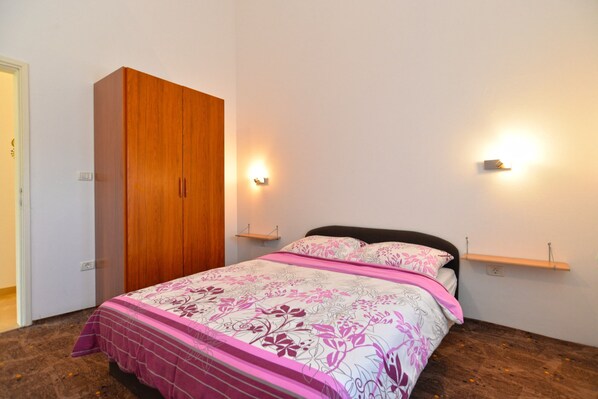 A bedroom with a bed, a wardrobe, and two wall-mounted lights. - Apartment 1773 (Medulin)