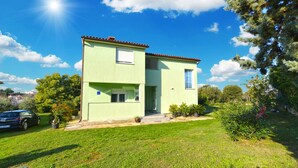 Un edificio a due piani con tetto piatto, un piccolo portico e un prato ben curato.