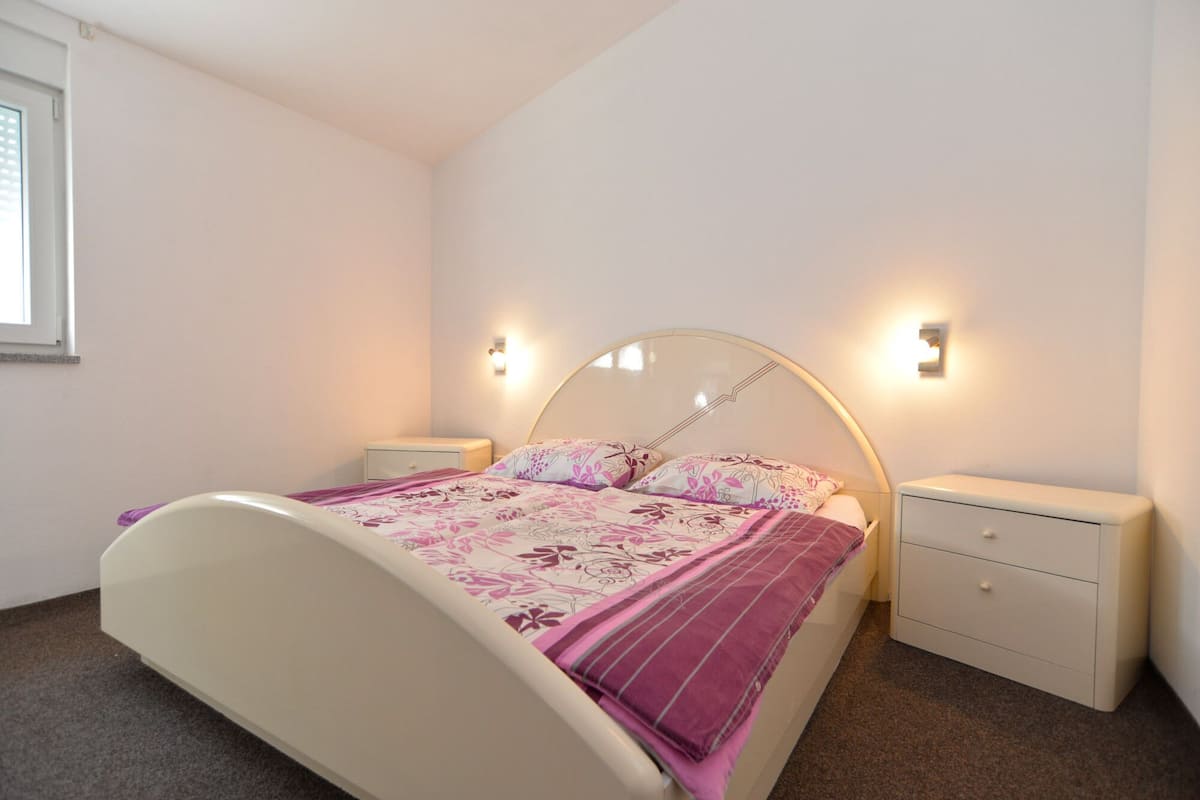 A bedroom with a bed, two bedside tables, and a nightstand.