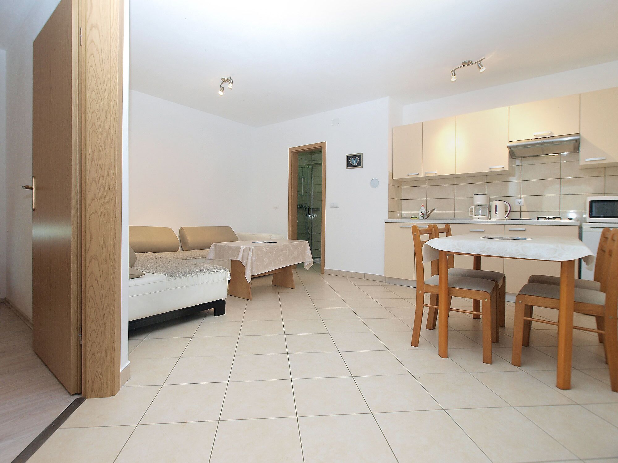 A compact living space with a kitchenette, a dining area with a table and chairs, a sofa, and a bed.