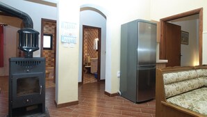 A kitchen with a wood stove, a refrigerator, and a bench. - Apartment 1775 (Medulin)